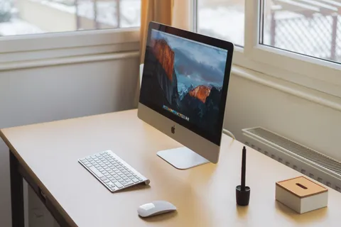 Desk with a desktop computer, keyboard and pen beside a bright window
